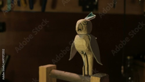 parrot turns its head and flaps its wings, funny wooden toy automaton, workshop interior