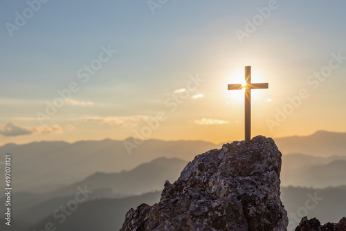 Silhouettes of crucifix symbol on top mountain with bright sunbeam on the sunset background