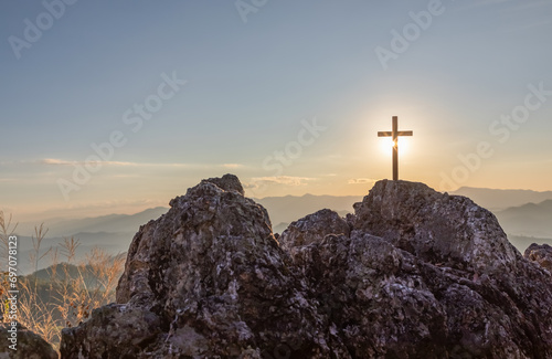 Silhouettes of crucifix symbol on top mountain with bright sunbeam on the colorful sky background