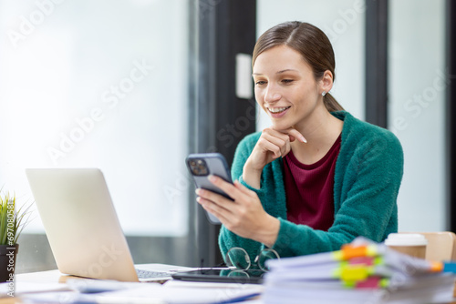 Portrait of Young canada american business woman using a mobile phone and works on a laptop computer in the workplace office
