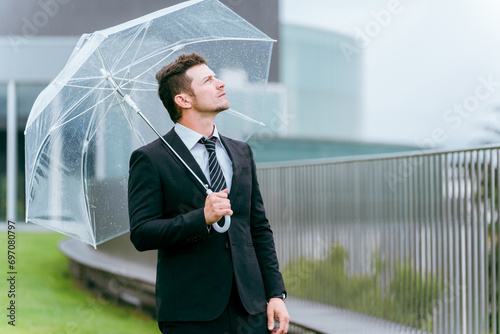 梅雨・台風の雨でビニール傘をさす外国人ビジネスマン 