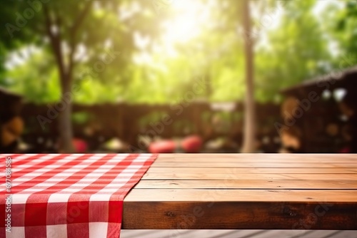 Empty table with red checkered towel, food ads. Tabletop with empty space. Picnic table on wooden deck, blurry backdrop. Promotional background.