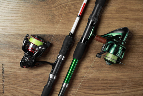 Fishing rods with spinning reels on wooden background, top view