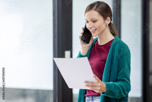 Attractive successful elderly businesswoman working in modern office, making phone call to potential client, having nice conversation, sitting at desk in front of open laptop