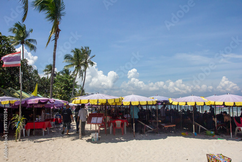 Tourists sat under beach restaurant umbrellas photo