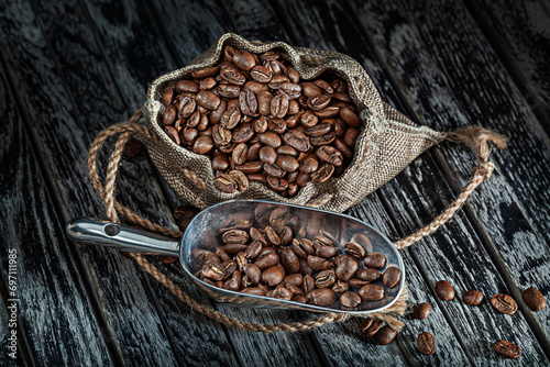Coffee Beans In Sack With Scoop On Vintage Wood Background.