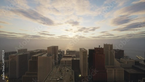 Sunset clouds drift off into the distance against the backdrop of a large city standing on the ocean.