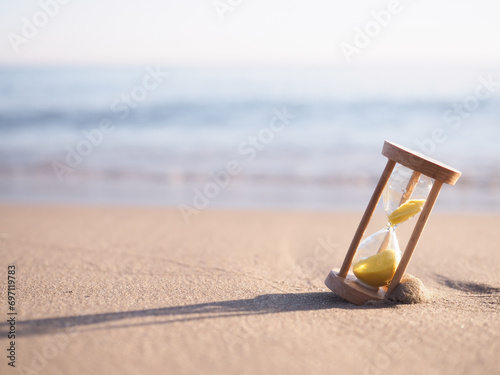 Hourglass on the beach in the sunset time. The concept about countdown to Summer, Travel, Vacation and Relaxation.