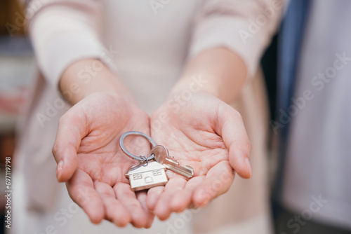 Happy woman a landlord hands keys signifying new home buy. Real estate concept close-up portrays success security and tenant happiness. Landlord's hand gives keys to the camera. Give me the key