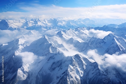 Aerial view of a majestic mountain range with snowy peaks and lush valleys.