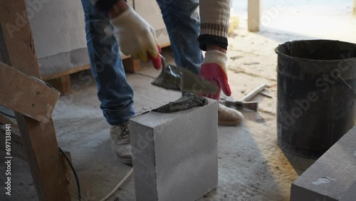 a builder applies concrete mortar to a brick photo