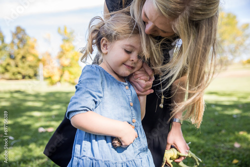 Mom kissing smiling daughter on head and holding her hand photo