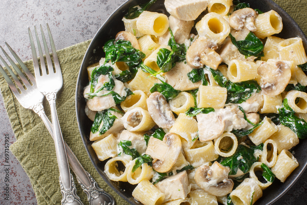 Italian pasta with chicken breast, mushrooms and spinach in creamy cheese sauce close-up in a plate on the table. Horizontal top view from above - obrazy, fototapety, plakaty 