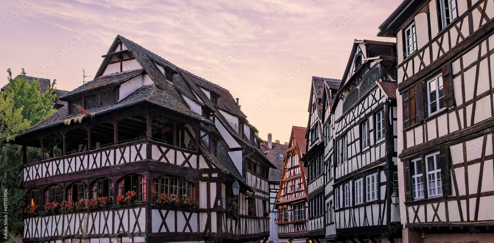 Ornate traditional half timbered houses with blooming flowers along the canals in the picturesque Petite France district of Strasbourg, Alsace, France at sunset