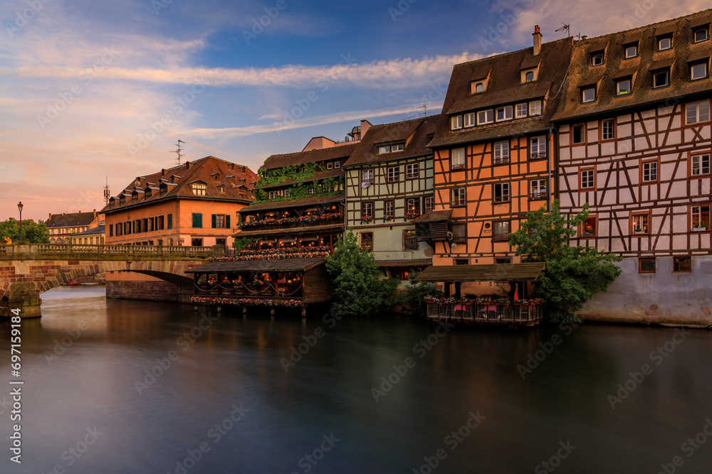 Ornate traditional half timbered houses with blooming flowers along the canals in the Petite France district of Strasbourg, Alsace, France at sunset Ornate traditional half timbered houses with blooming flowers along the canals in the Petite France district of Strasbourg, Alsace, France at sunset