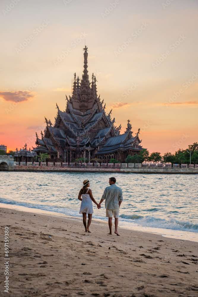 A diverse multiethnic couple of men and women visit The Sanctuary of Truth wooden temple in Pattaya Thailand. A diverse multiethnic couple of men and women visit The Sanctuary of Truth wooden temple in Pattaya Thailand.