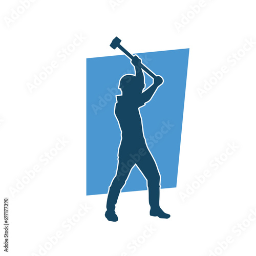 Silhouette of a worker in action pose using his sledge hammer tool.