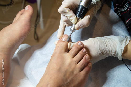 Girl in Beauty Salon doing pedicure to her male patient's toes