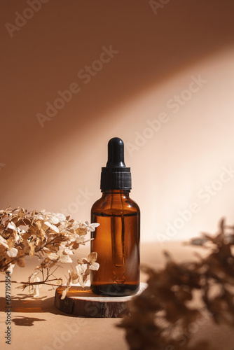 Dropper bottle on wooden podium with dry flowers on pastel beige background. Aesthetic, minimal beauty product packaging design.