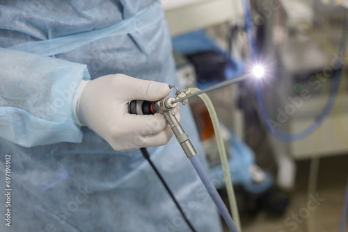 The veterinarian holds in his hand a rhinoscope with a glowing lamp at the end. A veterinarian in surgery checks the endoscope before performing a rhinoscopy. Veterinary rhinoscopy of a pet. photo
