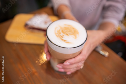 woman hands with latte on a wood table in cafe