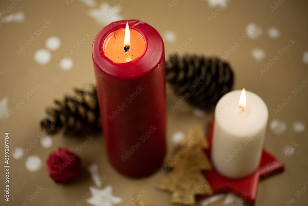 Christmas composition with candles, ornaments and pinecones, on handmade vintage background.
