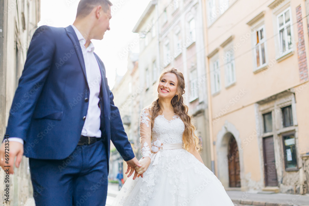 the groom in a blue suit holds the bride's hand and they walk th the groom in a blue suit holds the bride's hand and they walk th