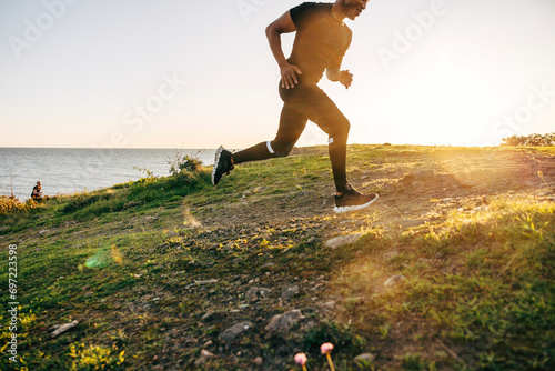 Young man running on hill near sea photo