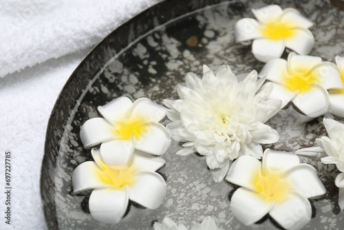 Bowl of water with flowers and towel on table  closeup. Spa treatment