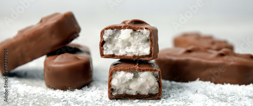 Delicious milk chocolate candy bars with coconut filling on grey table, closeup. Banner design photo