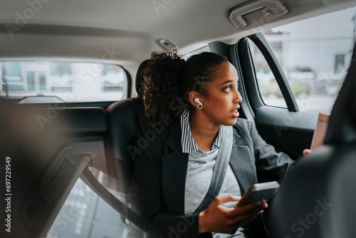 Businesswoman looking through window and talking on smart phone while sitting in car photo