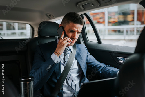 Businessman talking on smart phone while sitting with laptop in car