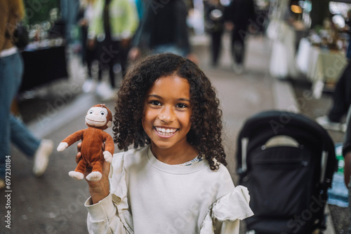 Portrait of happy girl holding toy monkey at flea market photo