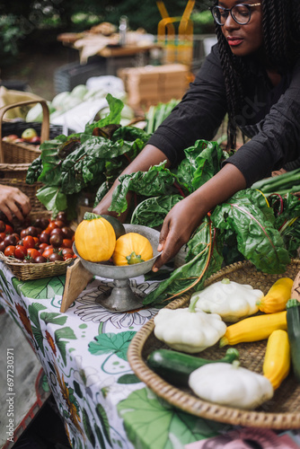 High angle view of female vendor keeping yellow courgettes on table at farmer's market