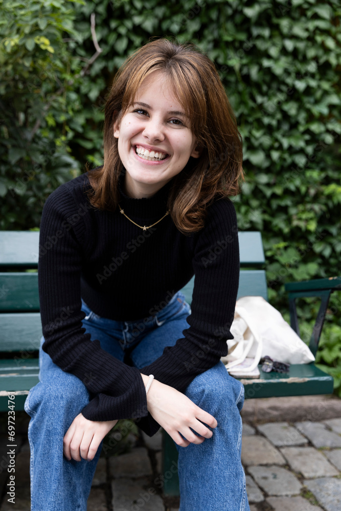 Portrait of happy young woman sitting on bench at park Portrait of happy young woman sitting on bench at park