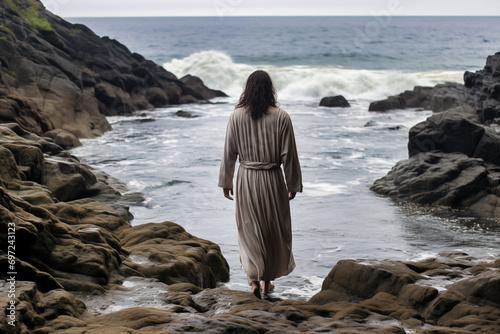 jesus is leaning over rocky shore looking at sea