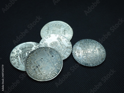 Spanish Escudo and Real coins in gold and silver on a black background photo