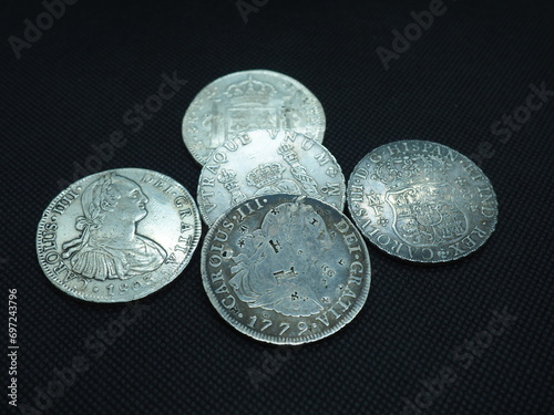 Spanish Escudo and Real coins in gold and silver on a black background