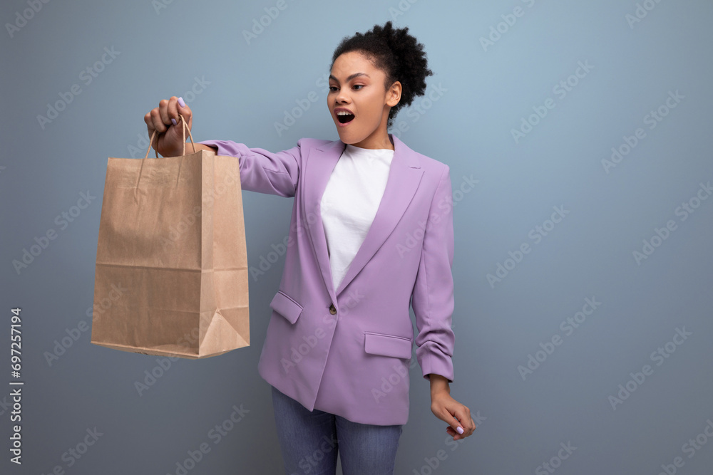 young pretty cute hispanic business woman with curly hair in a lilac jacket received delivery in an eco-friendly paper craft bag young pretty cute hispanic business woman with curly hair in a lilac jacket received delivery in an eco-friendly paper craft bag