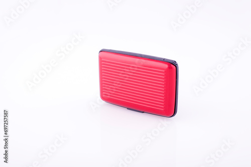 Red plastic credit card case on white reflective background. 