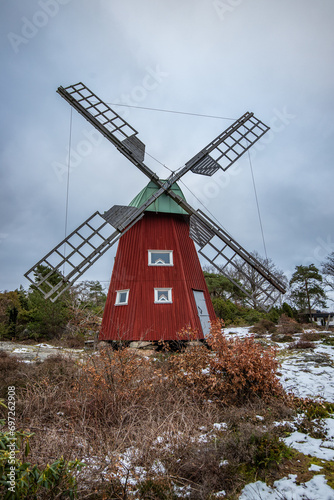 Typical historical red wooden windmill in a winter landscape. The building is located on a rock on the coast. Evening in Stenungsund  Sweden
