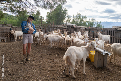 Woman holding a bby goat kid in the farm photo