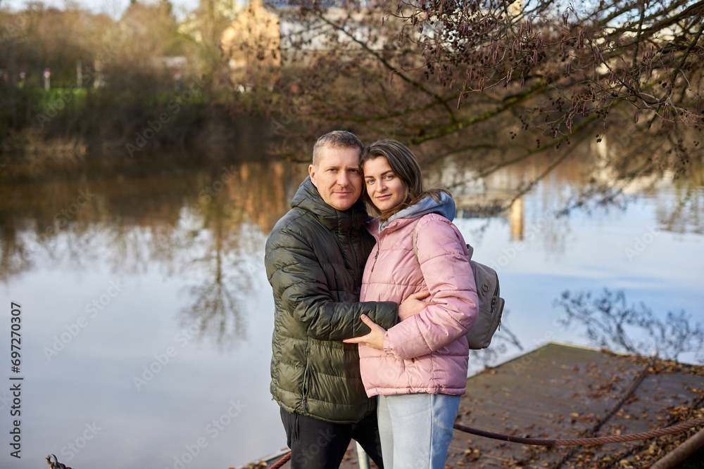 Loving couple on the shore of the pond in the park in autumn. A man and a woman. A couple, lovers on the shore of the lake on a walk. Autumn Romance by the Lake: Happy Couple's Lakeside Leisure Loving couple on the shore of the pond in the park in autumn. A man and a woman. A couple, lovers on the shore of the lake on a walk. Autumn Romance by the Lake: Happy Couple's Lakeside Leisure