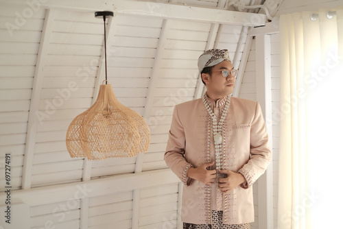 Asian Male Wedding person standing in front of wall with Beskap Blangkon Sundanese Culture