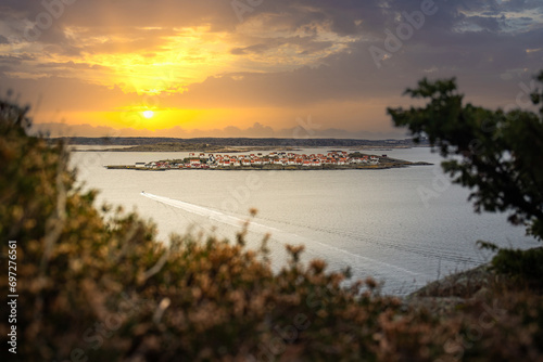 Landscape shot with a view of an island. Taken from a barren rock, you can see over the coast and the sea to the small island of Astol, Rönnäng, Sweden, which is built with typical Swedish houses photo