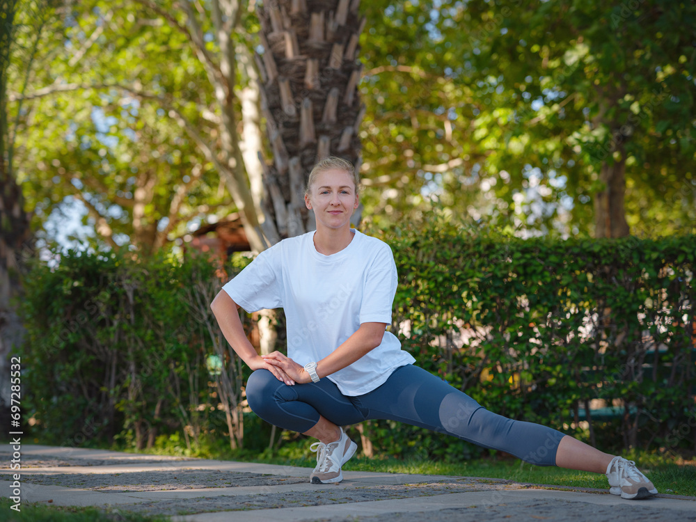 idea of healthy lifestyle and sports in a modern city. Female jogger. Fit young Caucasian woman stretching muscle in park before running and enjoying healthy outdoor. Fitness girl in public park.