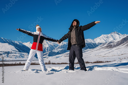 Young happy couple of tourists on mountains background in winter