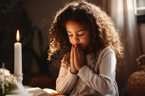 A black girl prays in front of a candle