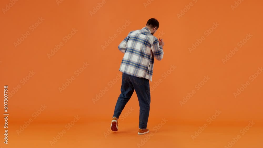 Handsome bearded man in plaid shirt, dancing happily, moving to music, having fun