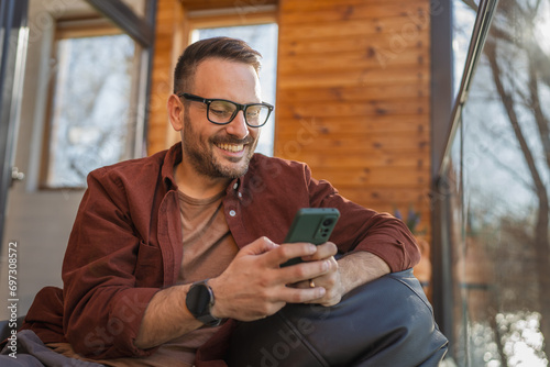 One adult man at home use smart phone app browse internet or send sms photo